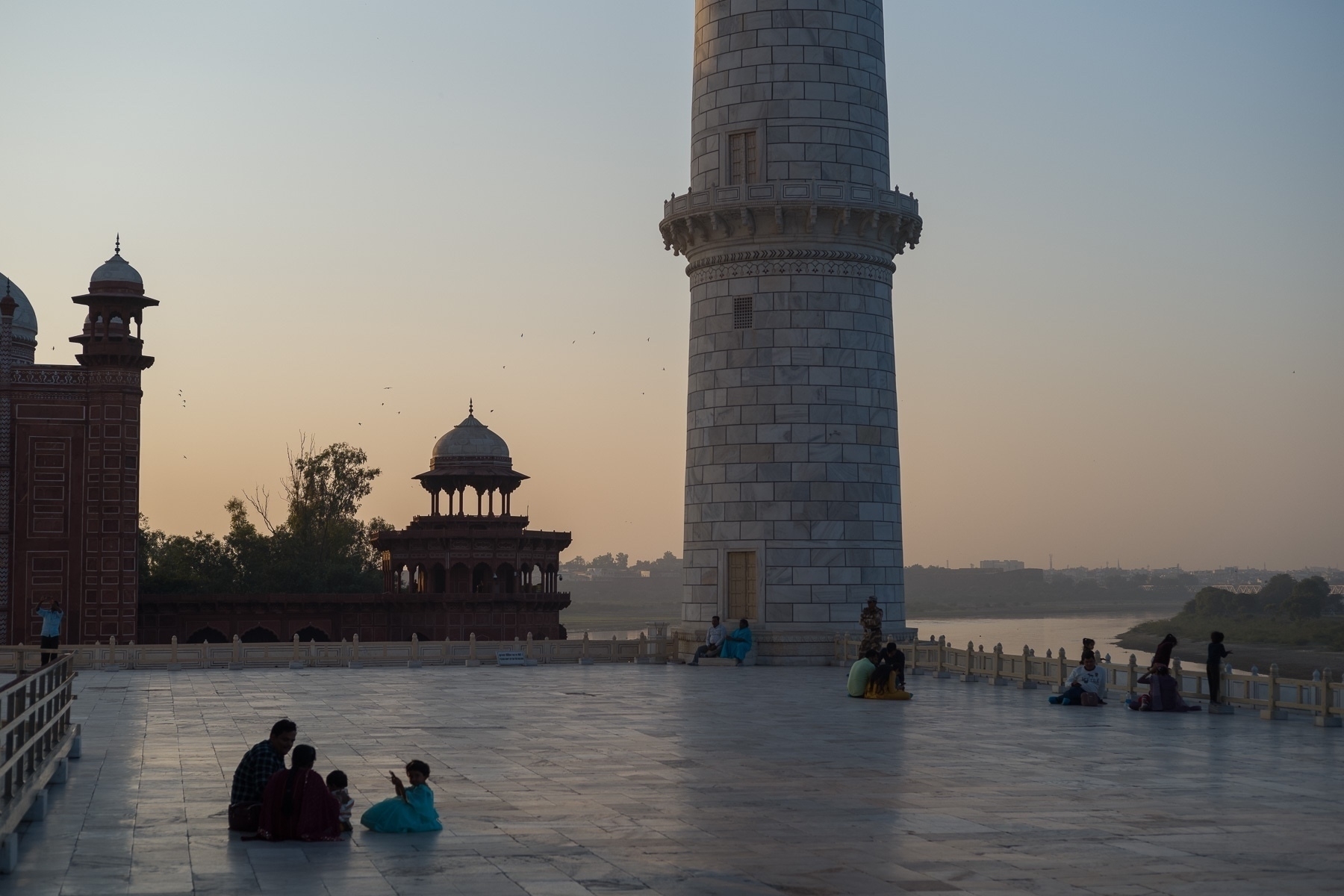 Plaza on the backside of the Taj Mahal at sunset with partial views of a minor, the mosque and the Yamuna river.
