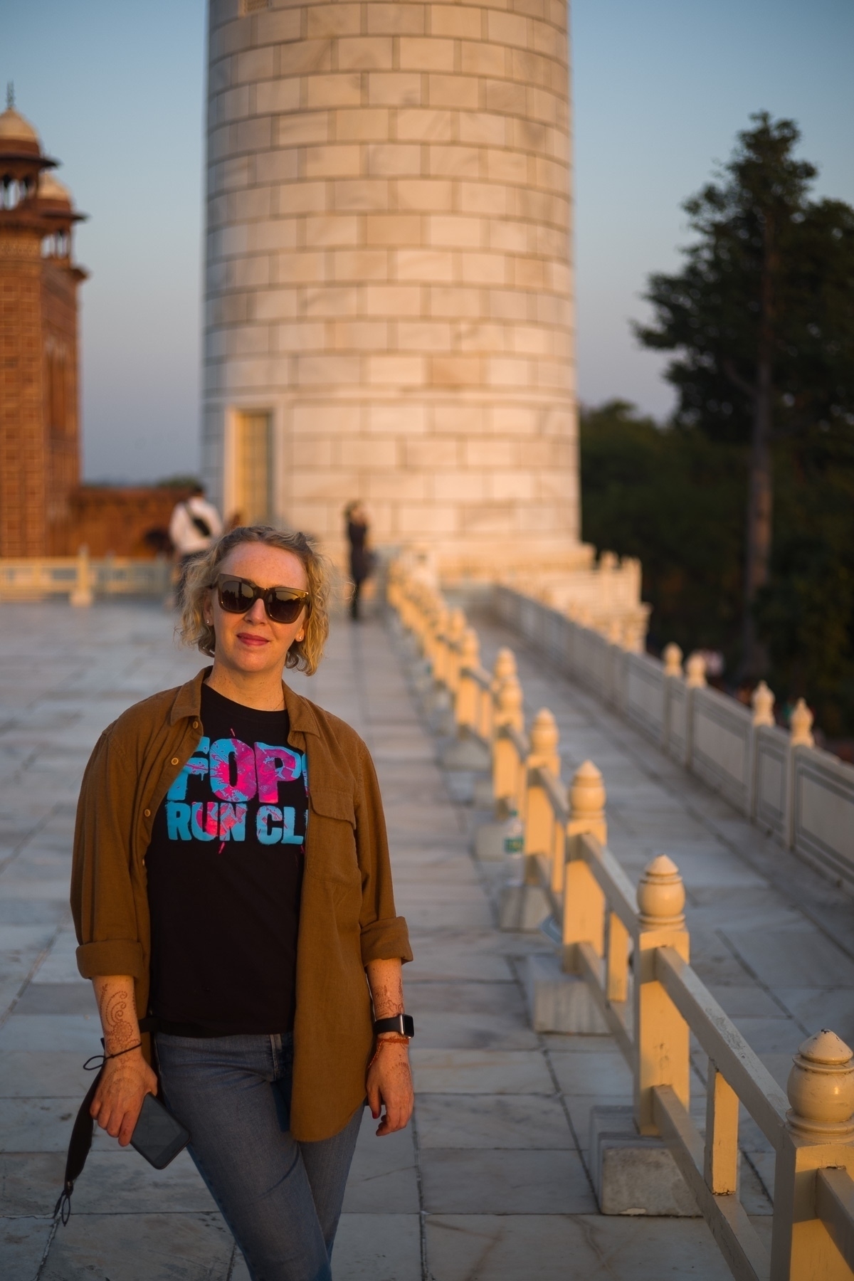 Jenni in front of one of the minars of the Taj Mahal with warm sunset light falling on both.